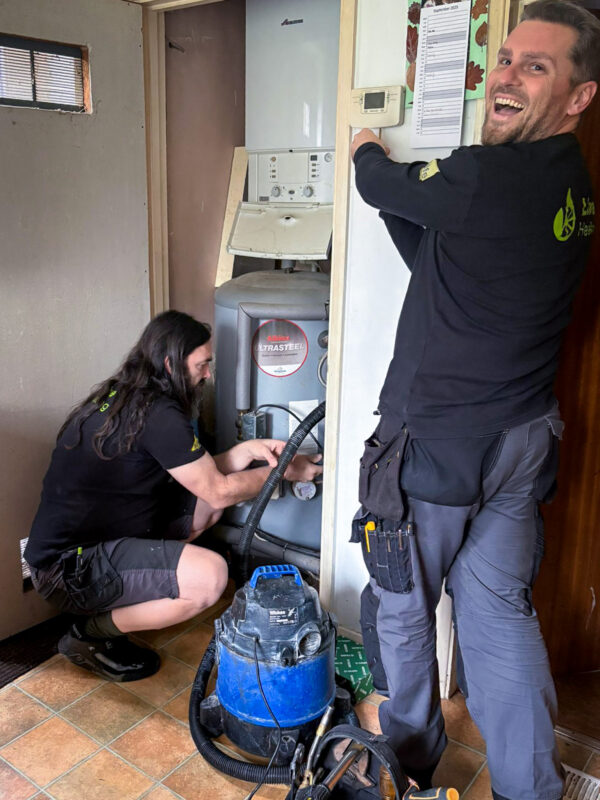 Gas Safe registered heating engineers install a smart heating control next to hot water cylinder.