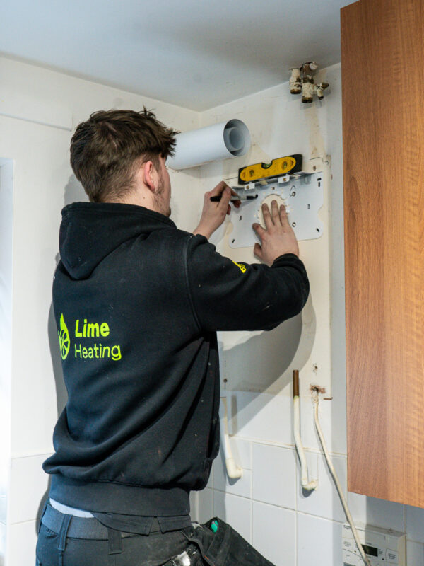 Carefully marking up the wall ready to install new gas boiler