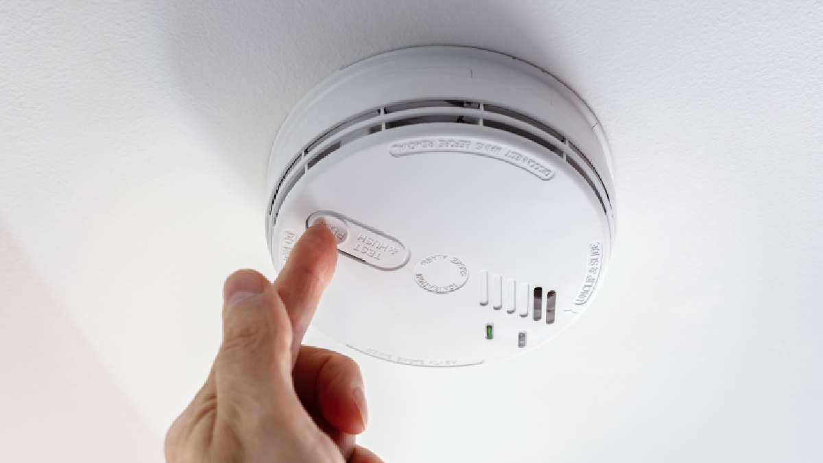 A person testing their CO alarm detector